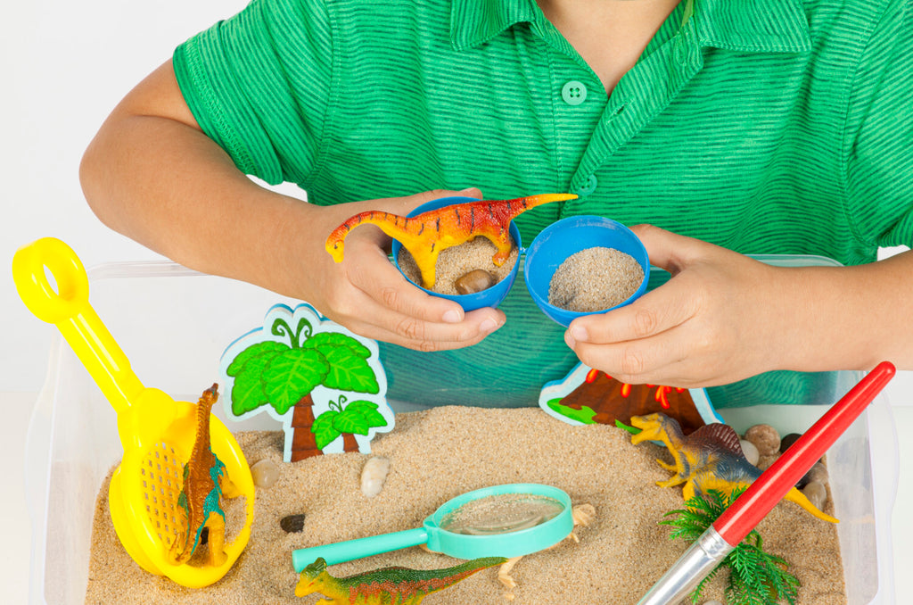 Creativity for Kids Sensory Bin Dinosaur Dig with kinetic sand, dinosaur fossils, and excavation tools